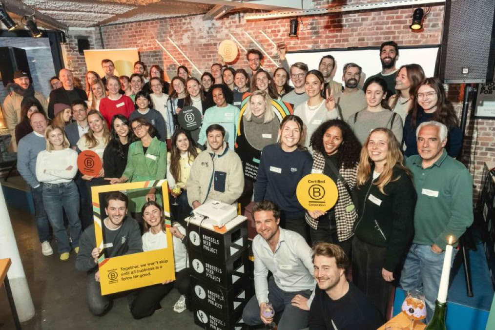 Groep mensen poseert samen in een binnenruimte, sommigen houden borden vast.